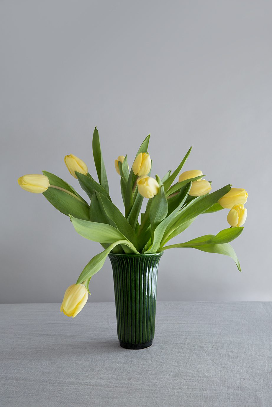 Glazed green slim vase with yellow tulips.