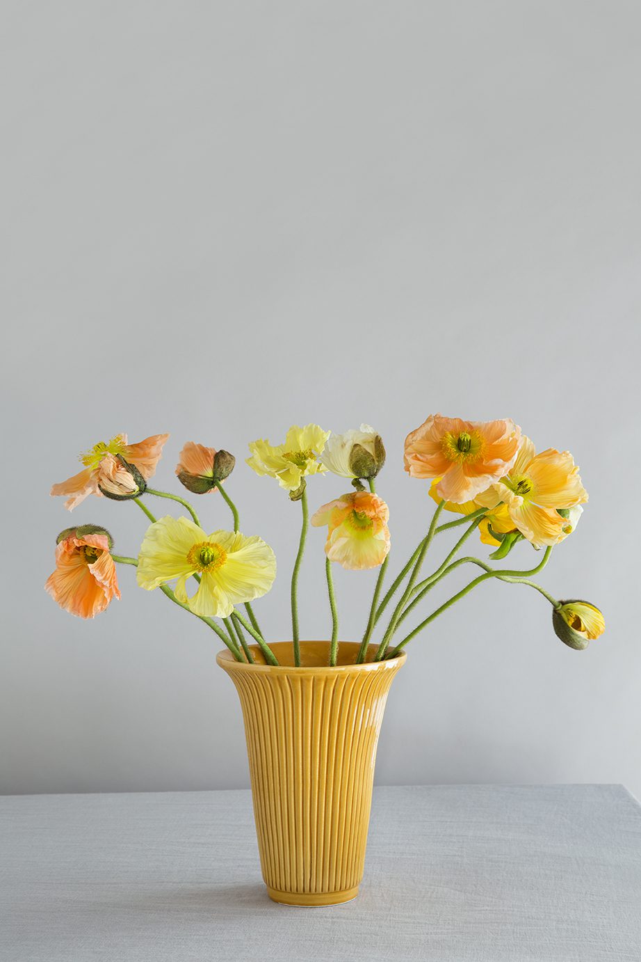 Glazed amber yellow vase with yellow flowers.