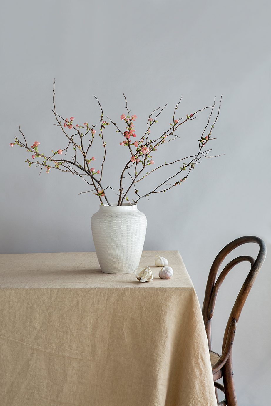 White glazed vase with branches on a table