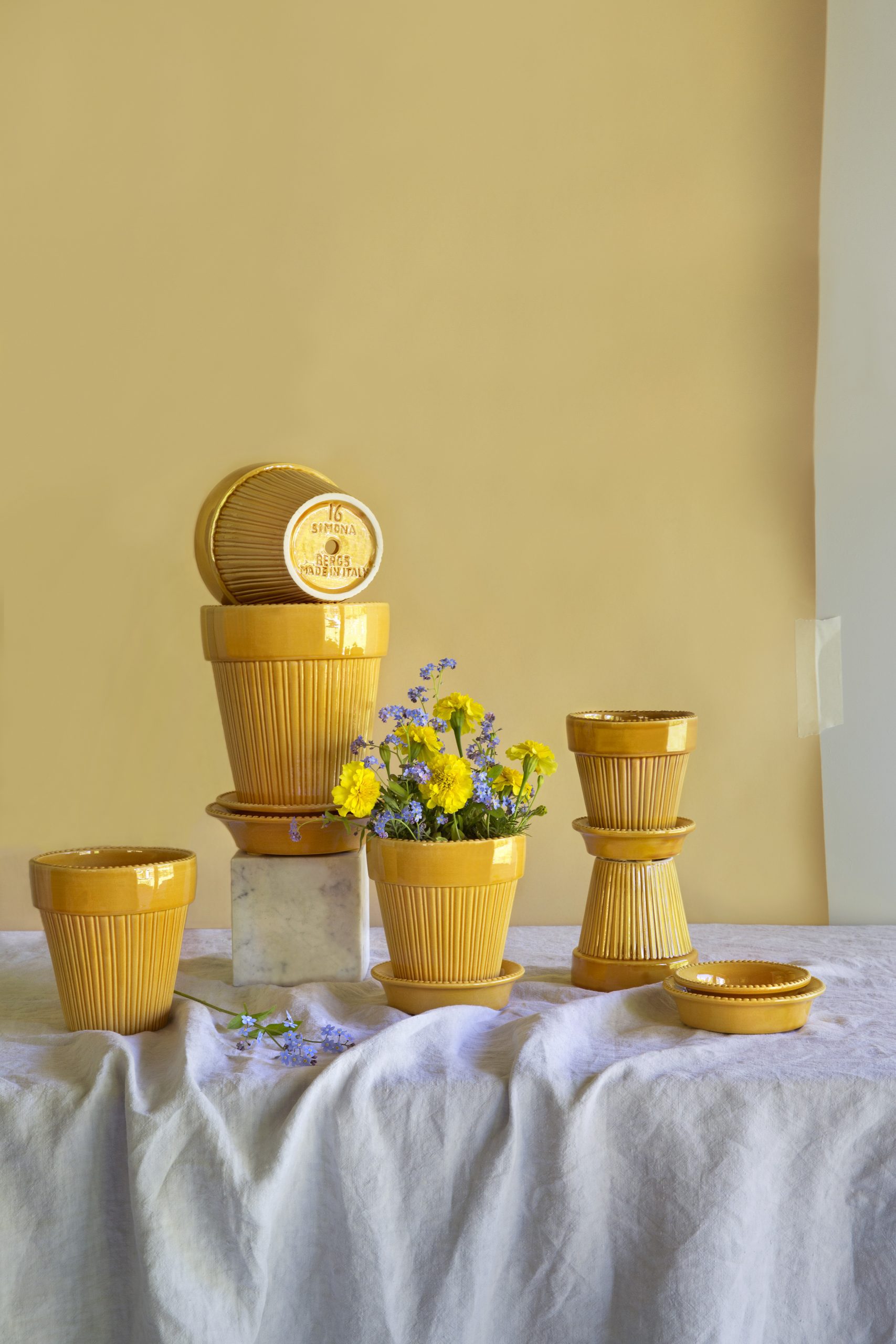 A collection of glazed amber yellow pots is arranged on a table.