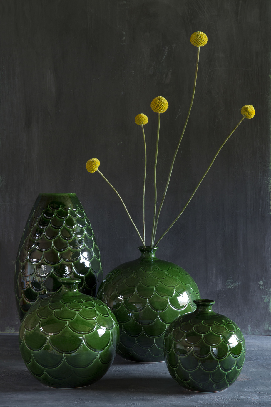 Round- and cone-shaped green vases with a pattern of petals.