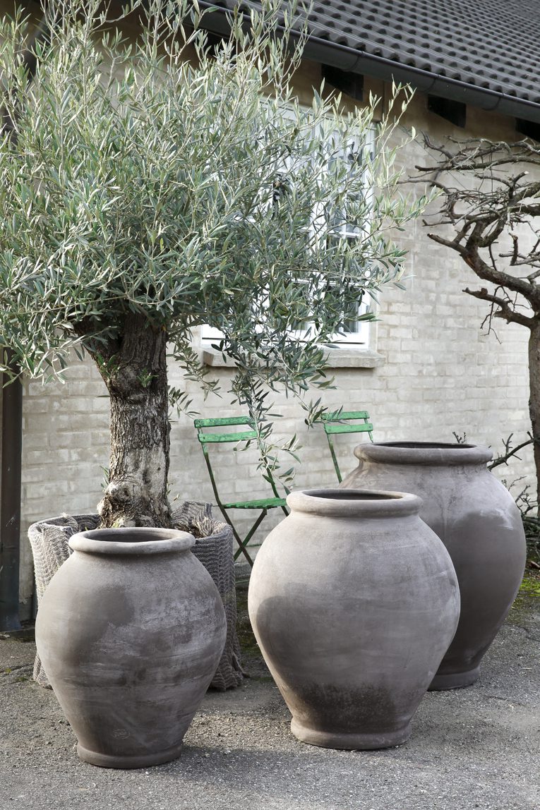 Three raw grey outdoor pots by a tree.