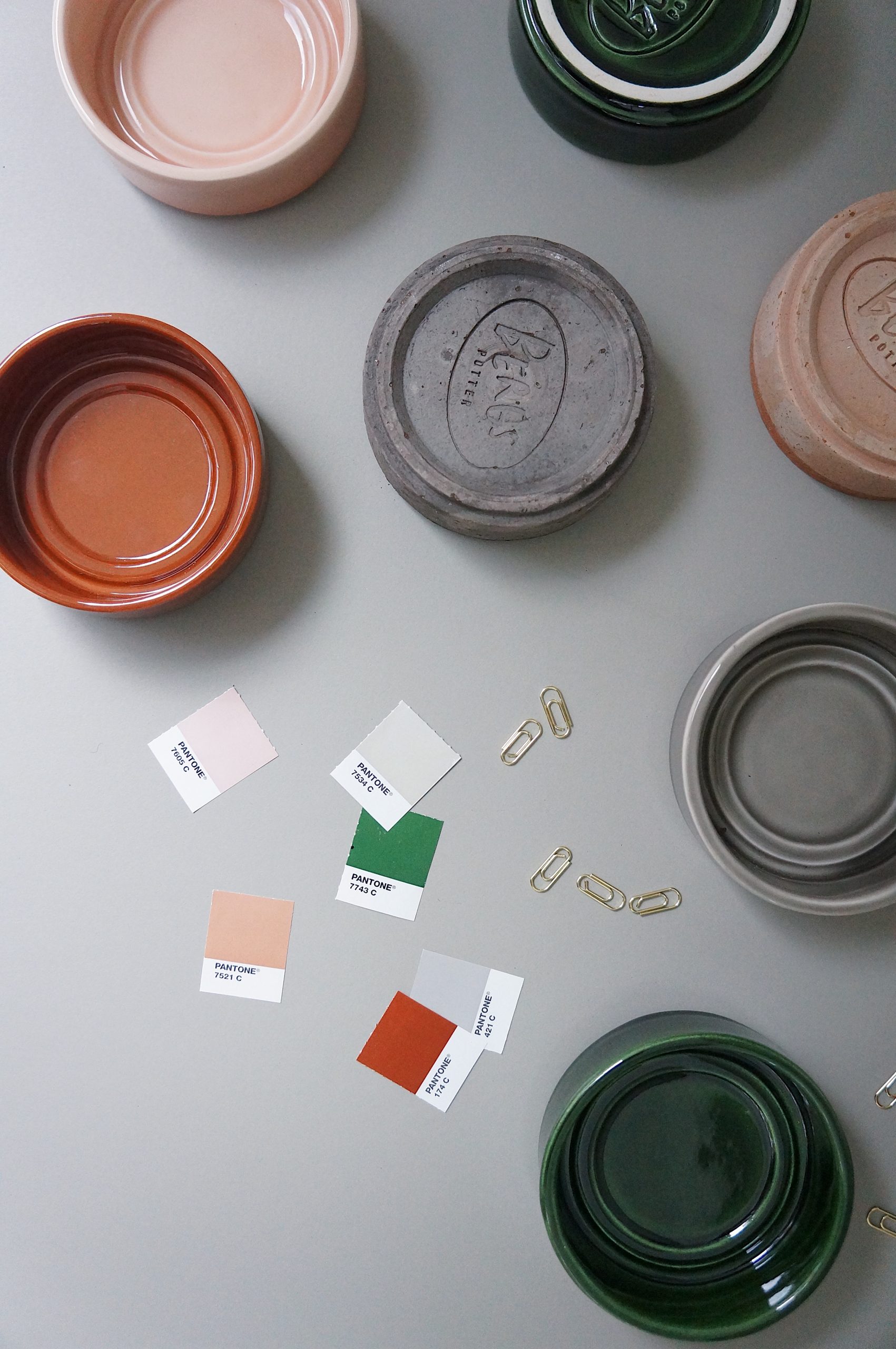 A mix of raw and glazed saucers in a variety of colours with Berg's signature stamp.