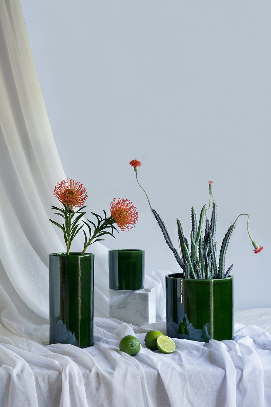 Cylindrical green glazed vase and flowerpots with flowers