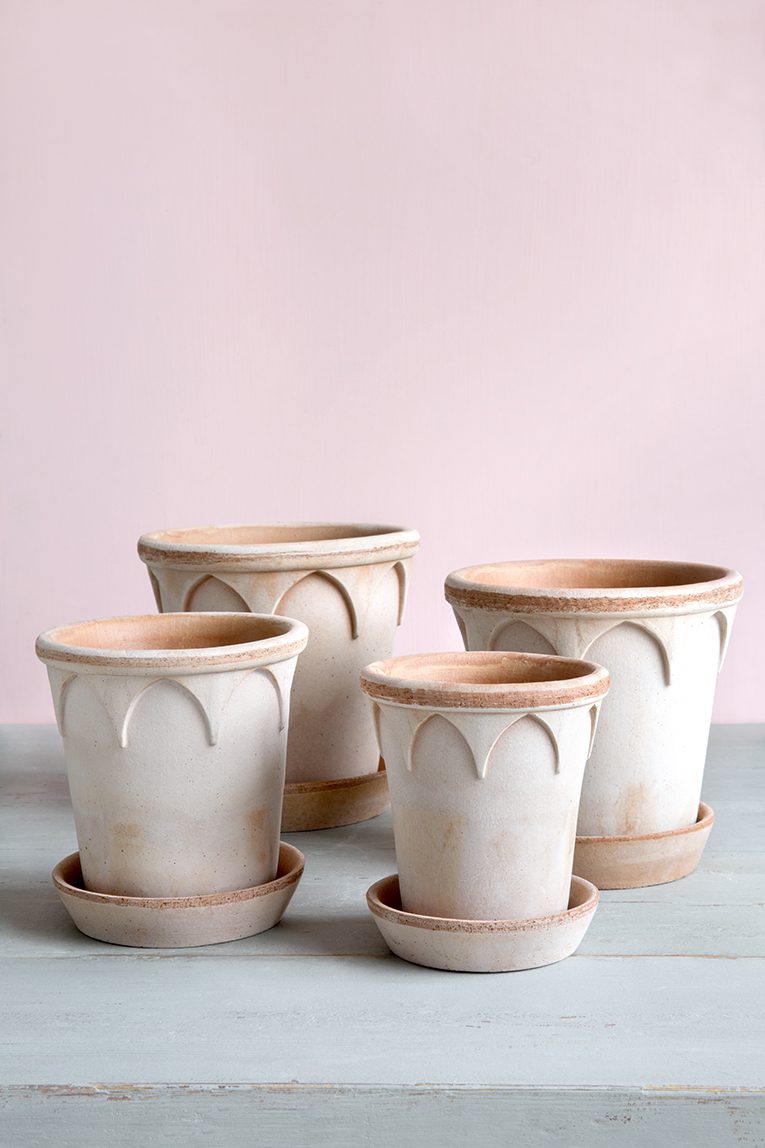 Four empty rose pots with saucers.