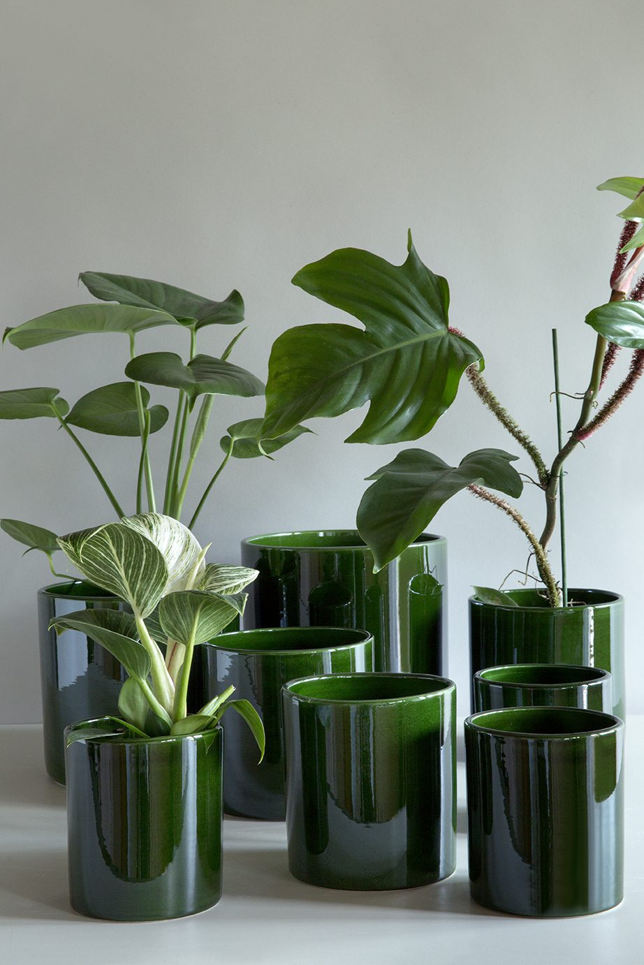 Collection of cylindrical glazed green pots in different sizes.