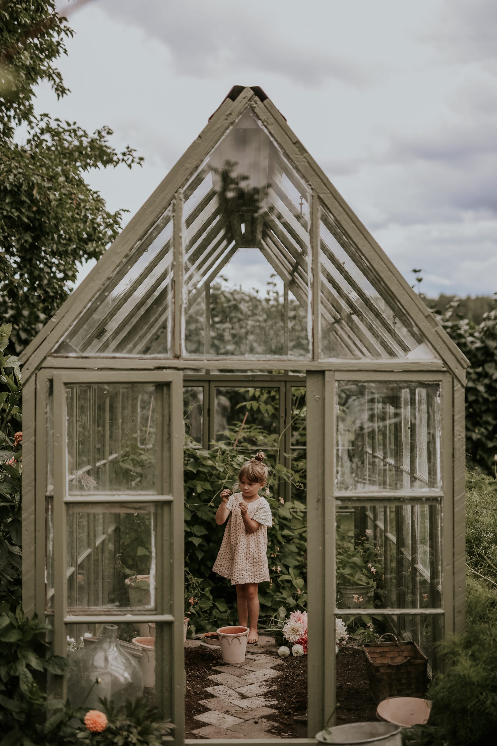 Anna Kubel's children's greenhouse in the family’s garden. The girl Bianca, is playing with seeds surrounded by terraccotta pots by Bergs Potter. Photo: Anna Kubel.